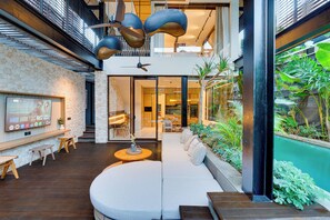 Un intérieur moderne avec un espace salon aux lignes courbes, un mur en pierre et une grande fenêtre donnant sur un jardin luxuriant.