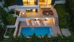 Une maison moderne dotée d’une piscine, d’un espace salon extérieur et d’un coin repas.