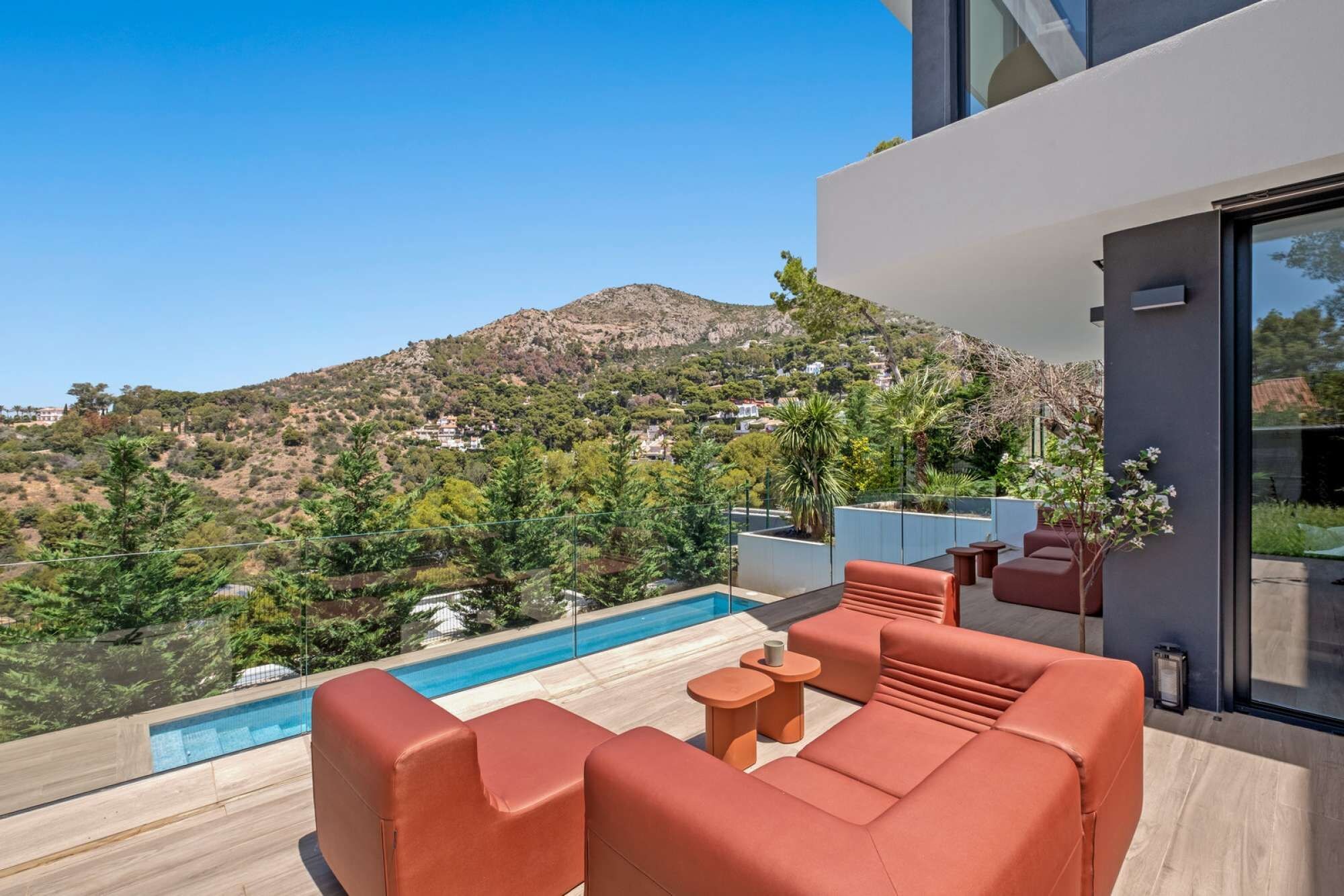 Ein moderner Poolbereich im Freien mit Sitzgelegenheiten und Blick auf eine Berglandschaft.
