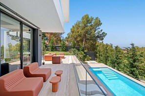 Un espace piscine extérieur moderne, doté de sièges et offrant une vue dégagée sur le paysage environnant.