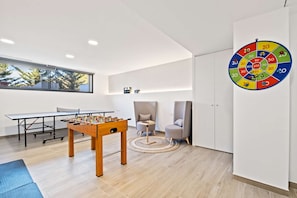 Une chambre moderne équipée d’un baby-foot, d’un jeu de fléchettes et d’une grande fenêtre.