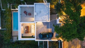 Une maison moderne avec une piscine, un patio doté de sièges et une voiture garée à l’extérieur.