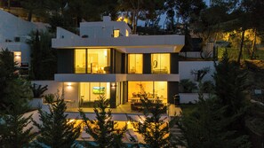 Una casa moderna de dos pisos con ventanas amplias, piscina y un jardín bien cuidado.