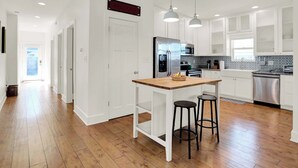 A modern kitchen with white cabinetry, a wooden island, and stainless steel appliances.