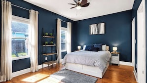 A bedroom with a bed, bedside tables, a ceiling fan, and a window with curtains.