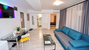 A modern living room with a sofa, a glass coffee table, a dining table with chairs, and a TV mounted on the wall. - Bucharest Old Town Apartments (Bucharest)