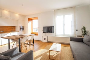 A modern apartment with a kitchen, dining area, living room, and a large window.
