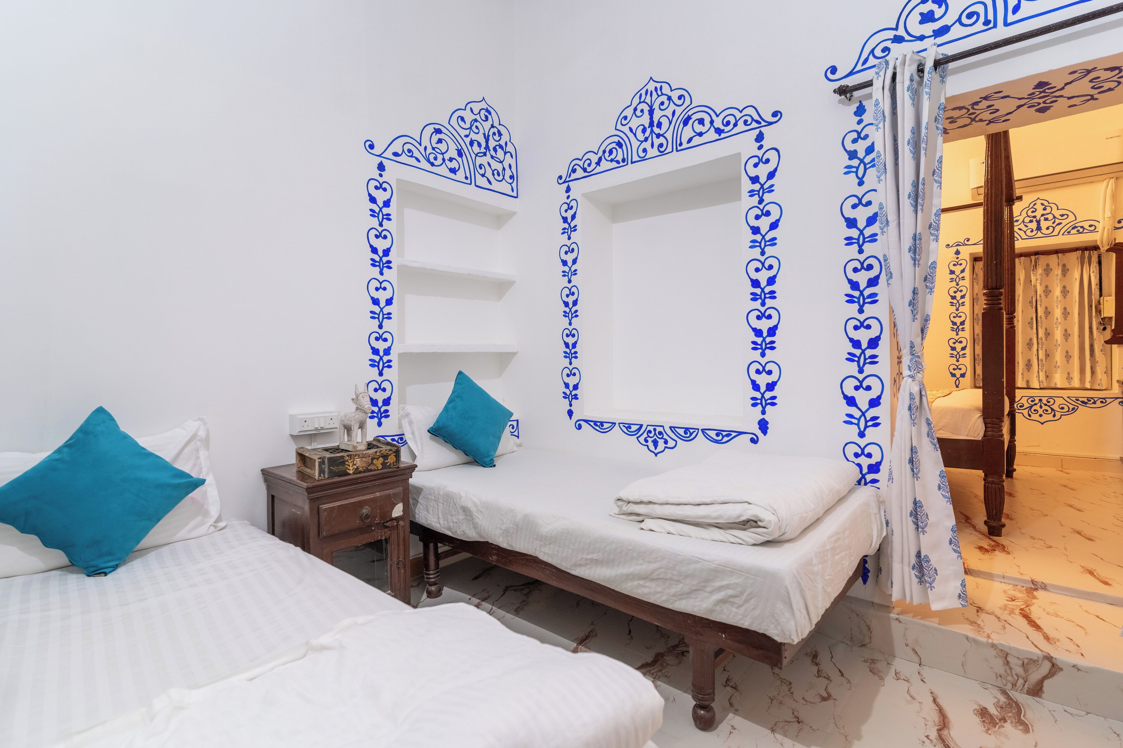 Ein Zimmer mit zwei Betten, einem Nachttisch und einem Spiegel mit blauen Zierrahmen.