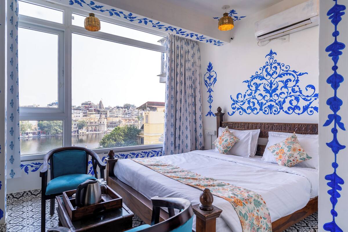 Habitación de hotel con una cama grande, vistas al río, una silla y decoración en la pared.