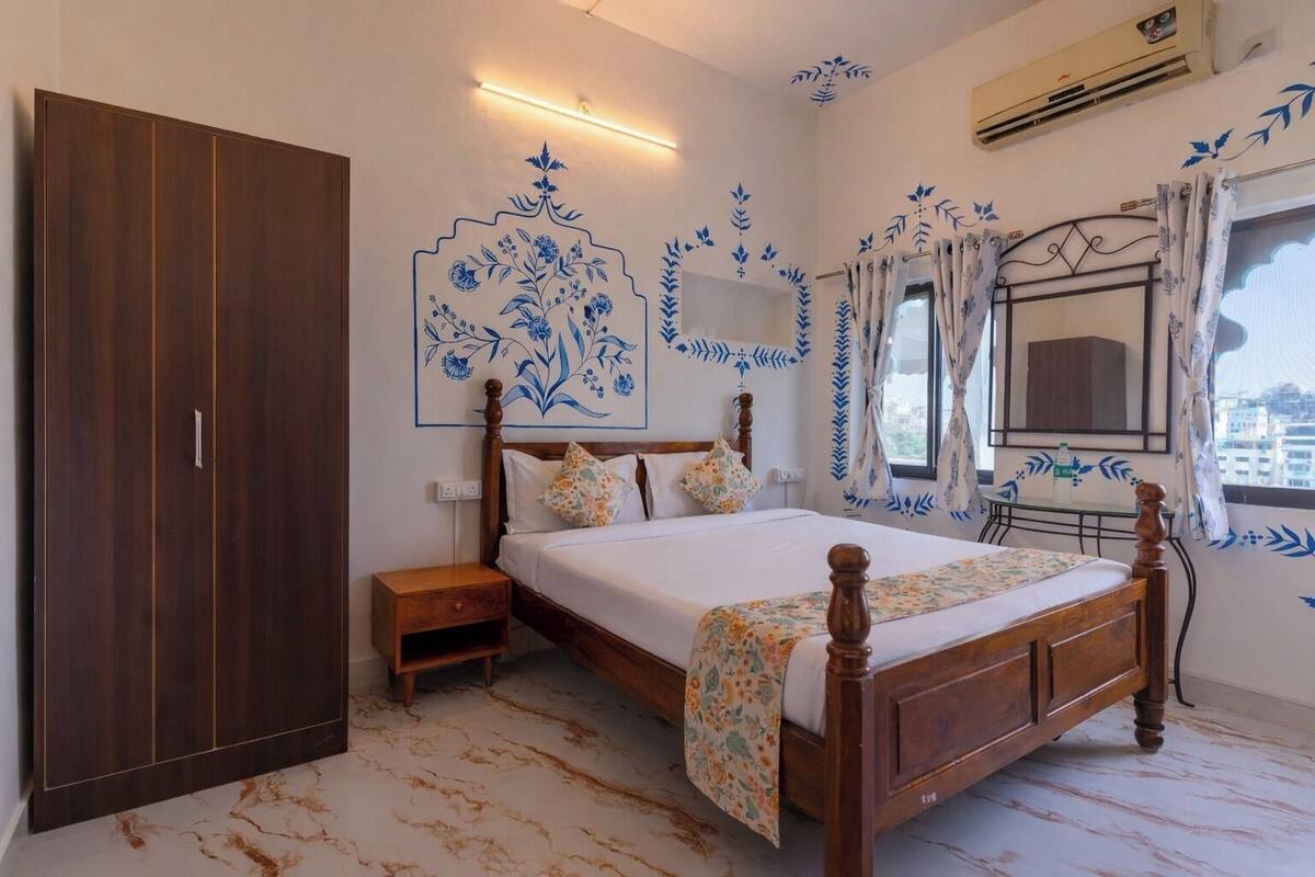 Un dormitorio con un armario grande, una cama con ropa de cama floral, una mesita de noche y un espejo.