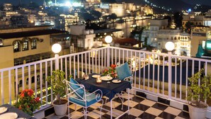 Ein Balkon mit Schachbrettboden, einem Tisch für zwei Personen und Topfpflanzen.