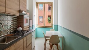 A compact kitchen with a window, a dining area with a table and chairs, and wooden cabinets.
