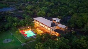 An aerial view of a modern hotel with a swimming pool, surrounded by lush greenery. - Chaarya Lake  (Yala)