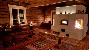 Un interior acogedor de cabaña con chimenea, bancos de madera y una mesa de comedor rústica.