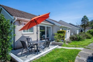 Una propiedad residencial con patio, mobiliario exterior y zona cubierta.