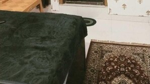 Une pièce avec un lit, une fenêtre, une porte et un mur décoré de motifs.