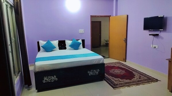 Quarto com cama, guarda-roupa, espelho, tapete e televisão.