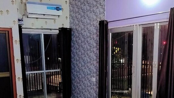 Une chambre avec un lit, un mur décoré de motifs, une porte-fenêtre coulissante et un appareil de climatisation.