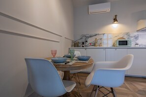 Un coin repas avec une table ronde, deux chaises et une cuisine en arrière-plan.