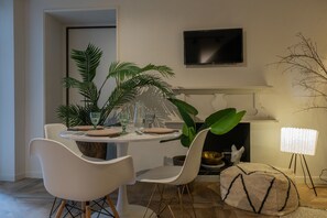 A dining area with a round table, white chairs, and a potted plant. - Design in Corso Francia 1 by Wonderful Italy (Torino)