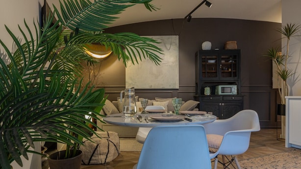 A modern living room with a round dining table, blue chairs, a sofa, and a cabinet with kitchen appliances. - Design in Corso Francia 1 by Wonderful Italy (Torino)