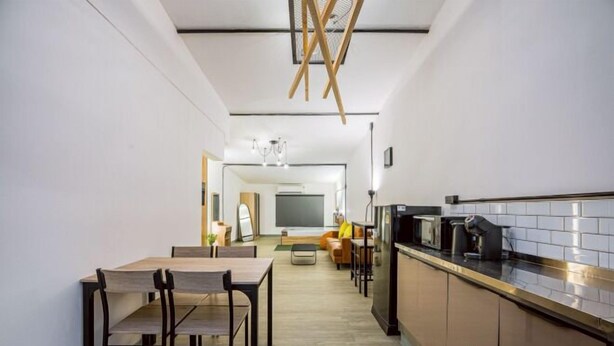 A modern kitchen with a dining area, wooden ceiling beams, and a large flat-screen TV. - Oasis Suites - Pattaya - Huge Modern Apartments (Pattaya)