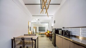 A modern kitchen with a dining area, wooden ceiling beams, and a large flat-screen TV. - Oasis Suites - Pattaya - Huge Modern Apartments (Pattaya)