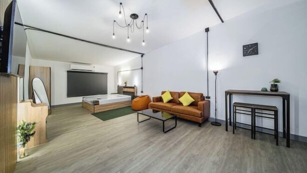 A modern living room with a sofa, coffee table, and a TV. - Oasis Suites - Pattaya - Huge Modern Apartments (Pattaya)