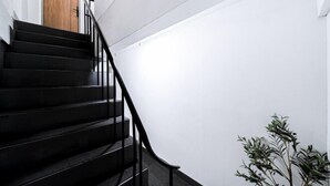 A staircase with black railings leading to a wooden door. - Oasis Suites - Pattaya - Huge Modern Apartments (Pattaya)
