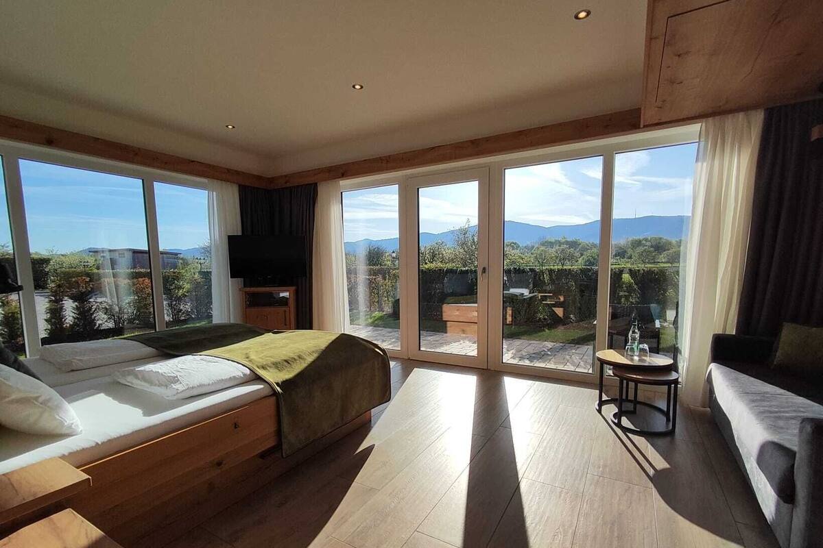 Un dormitorio amplio con una cama grande, televisión y balcón con vistas al campo.