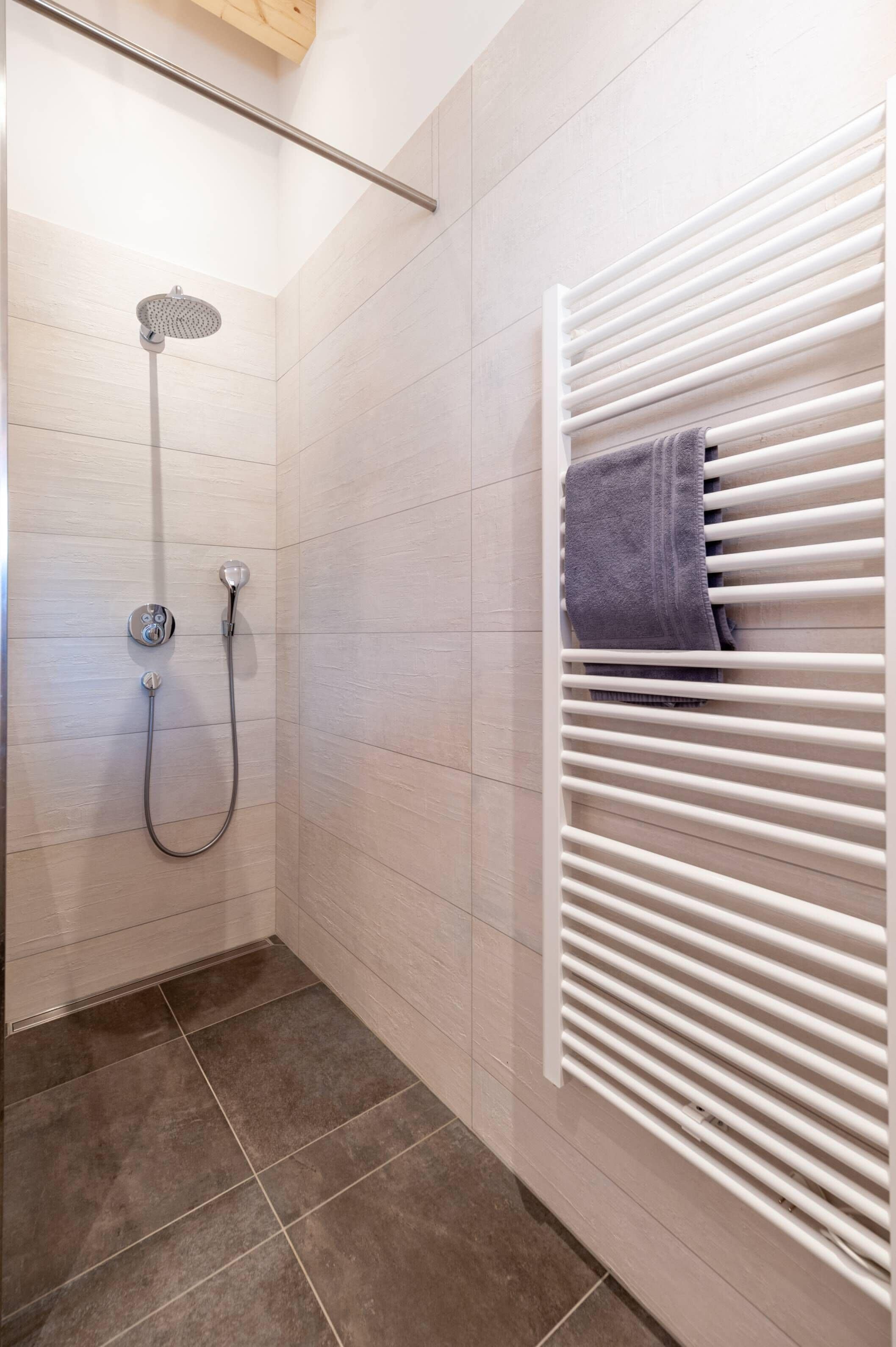 A shower with a handheld showerhead and a wall-mounted control panel.