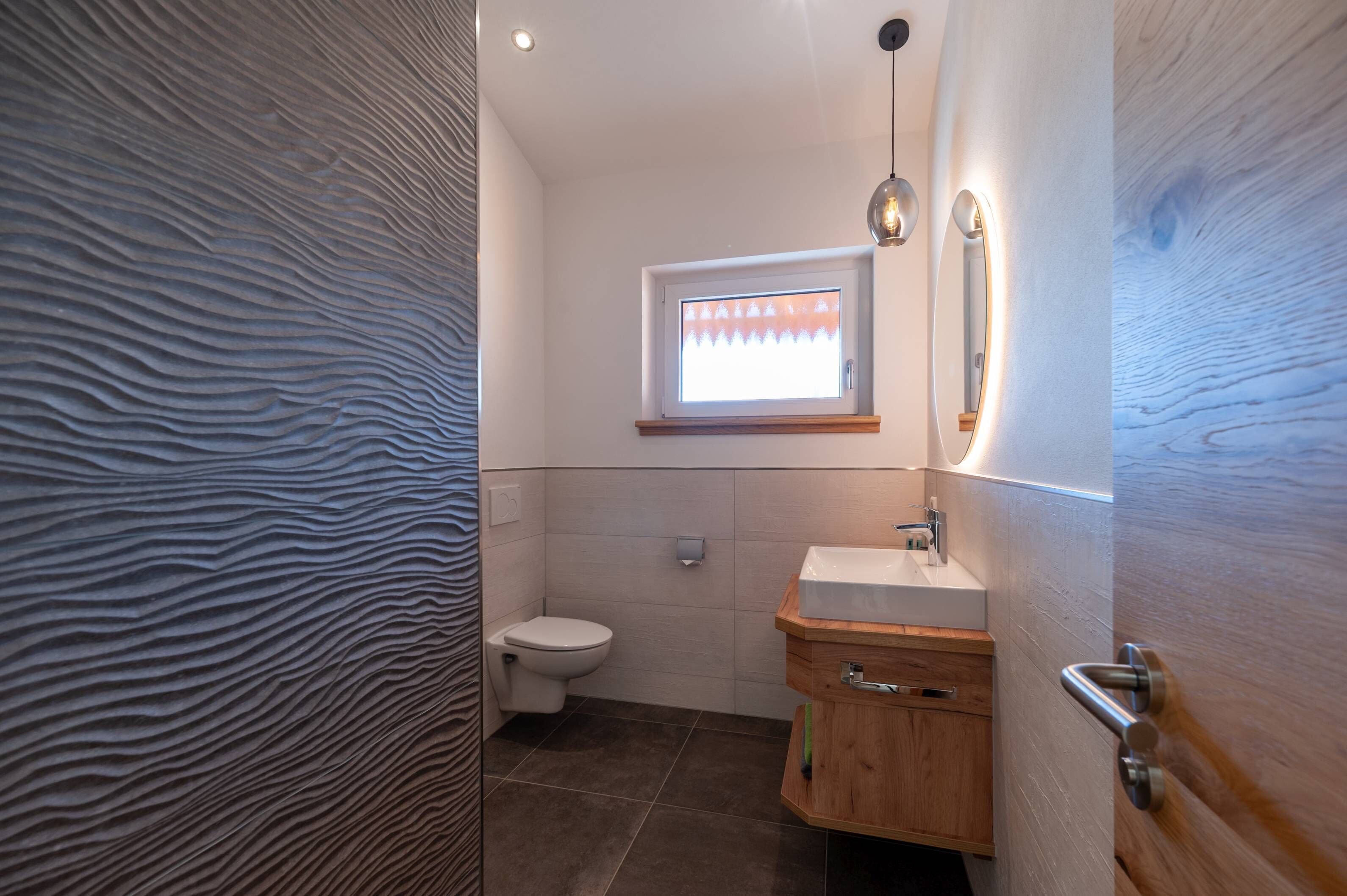 A modern bathroom with a toilet, a sink, and a window.