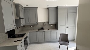 Une cuisine moderne avec des meubles gris, un four encastré et une chaise grise.