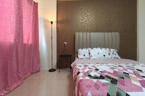 Une chambre à coucher avec un lit, une table de chevet, une lampe et un rideau.