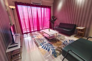 Una habitación con sofá, una mesita, televisor y cama.