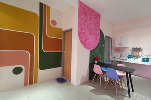 Une cuisine moderne avec un coin repas, une décoration rose suspendue et une petite table avec des chaises.