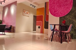 Un moderno vestíbulo de hotel con una recepción, una zona de estar con sillas y una gran decoración abstracta en la pared.