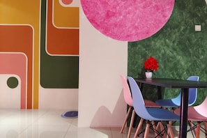 Un interior moderno con una mesa redonda y sillas, una pared texturizada en verde y un adorno circular rosa.