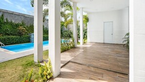 Un área de patio techada con piscina, pilares blancos y una puerta.