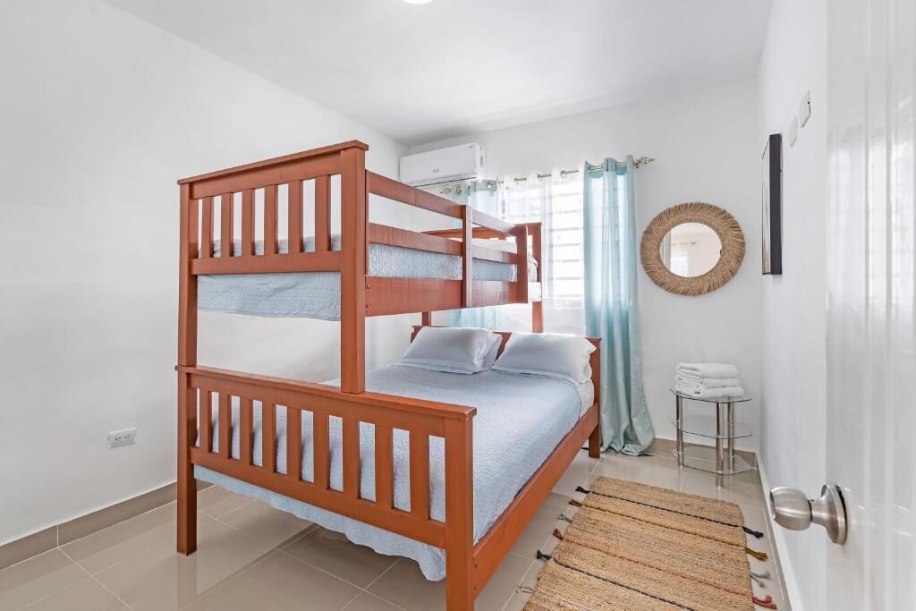 A bunk bed room with a small table and a mirror on the wall.