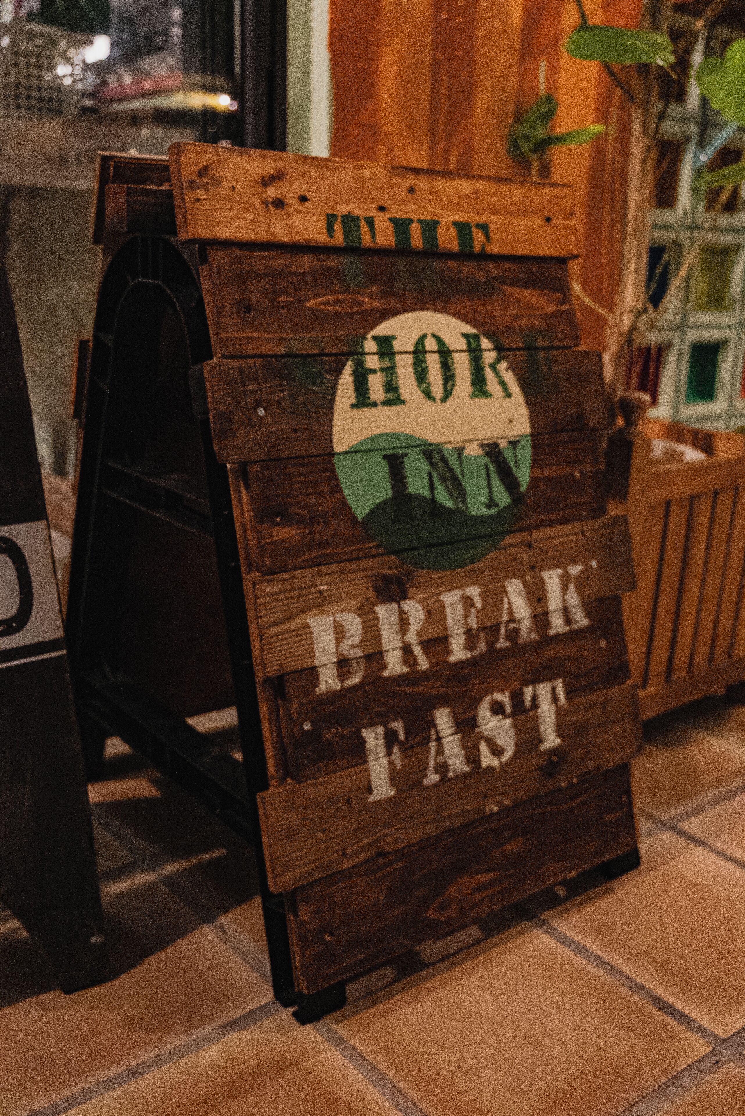 Un letrero de madera con el texto 'HOR INN BREAKFAST FAST'.