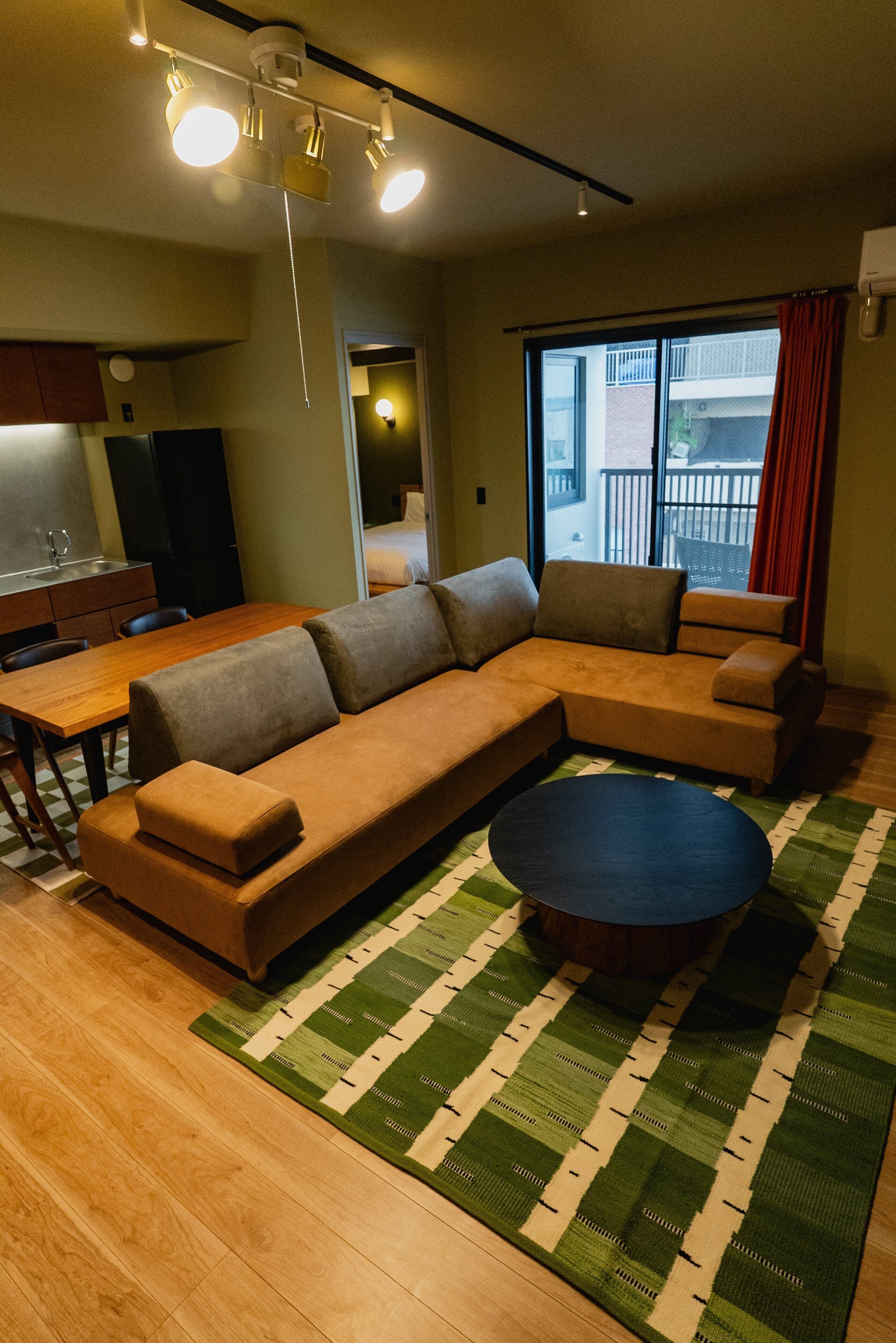 Una sala de estar con un sofá seccional, una mesa de comedor y una mesa de centro.