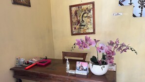 Een houten bureau met een vaas roze orchideeën, een rode dienblad en een tijdschrift.