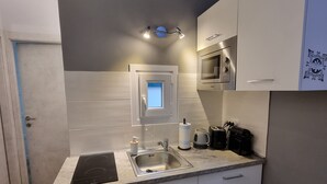 A modern kitchen with white cabinets, a built-in stove, a sink, and a microwave.