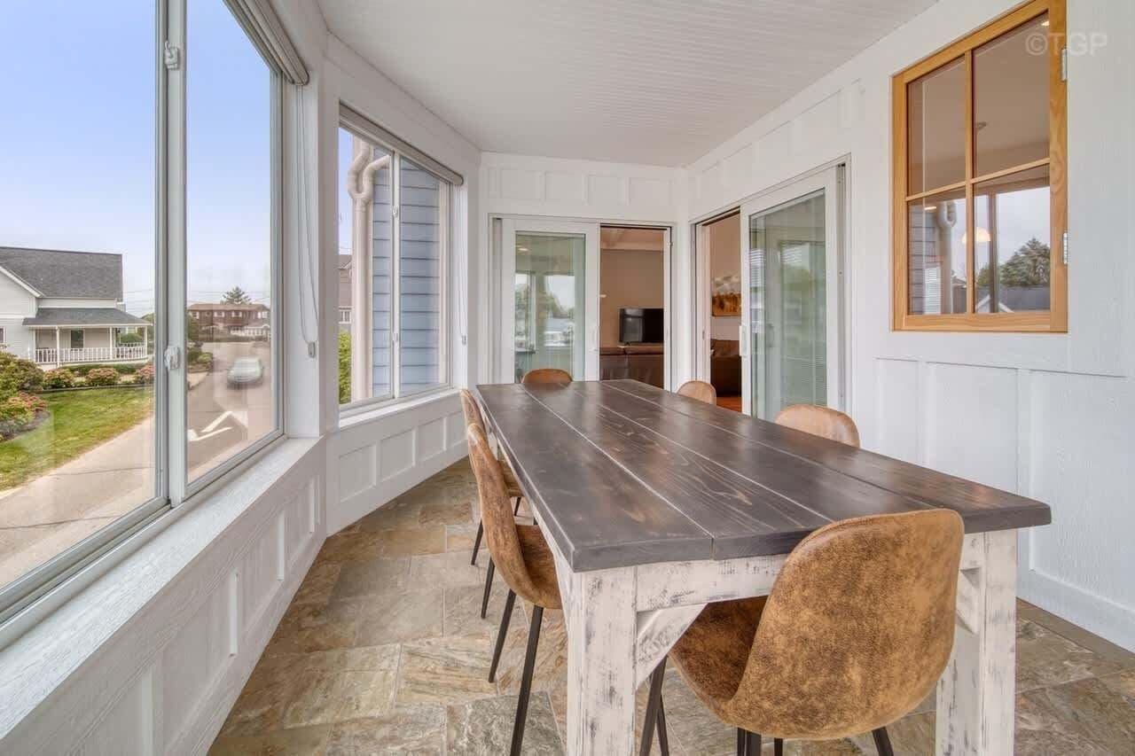 Un espace repas avec une longue table, des chaises et de grandes fenêtres.