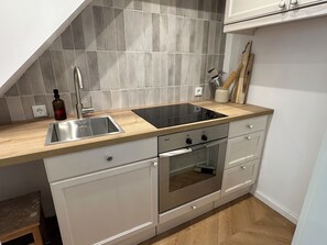 Eine Küche mit Spüle, Herd, Backofen und einer Holz-Arbeitsplatte.