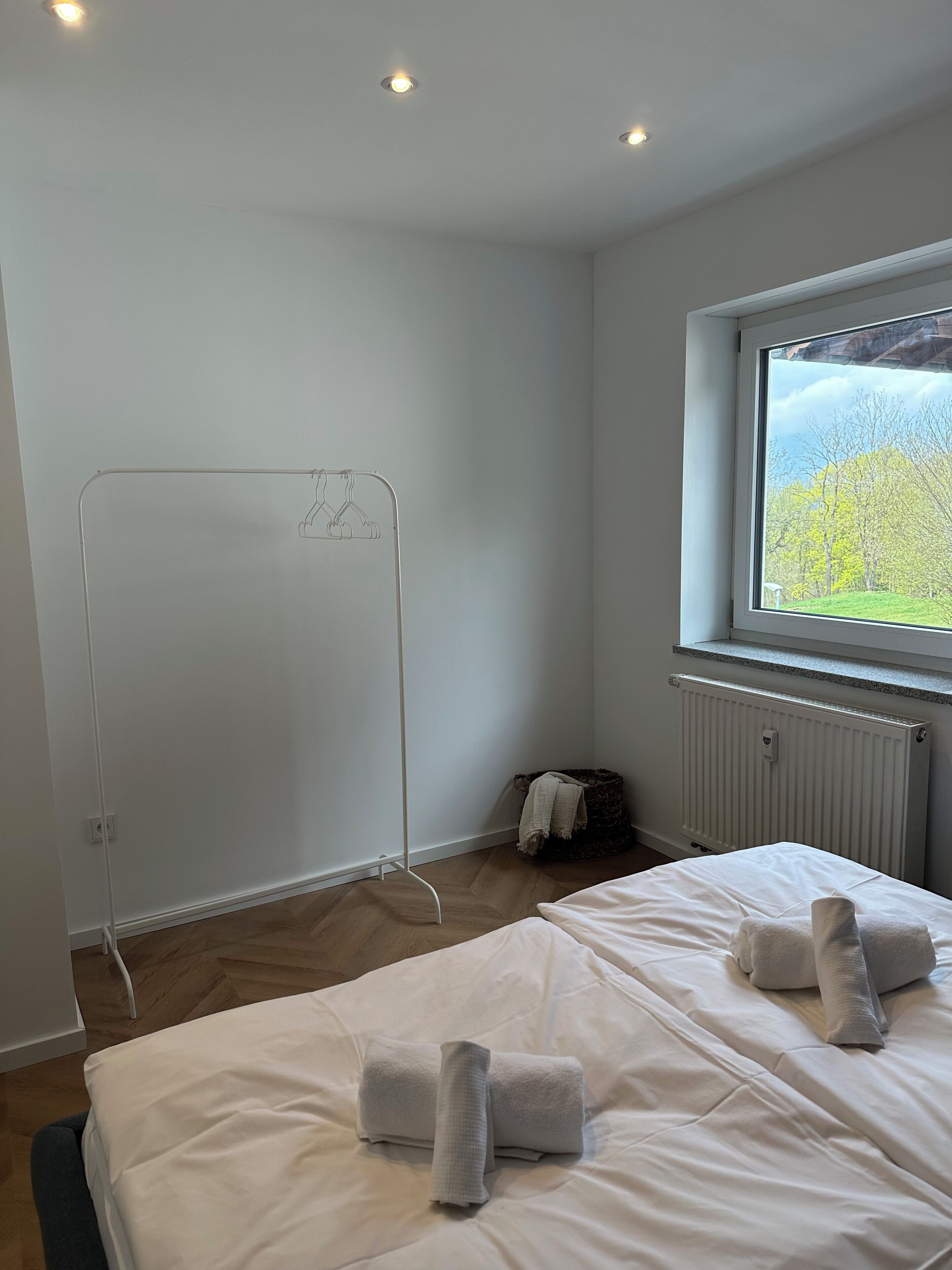 Una camera d'albergo con un letto, un termosifone, una finestra vista e uno stendibiancheria.