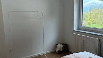 Una camera d'albergo con un letto, un termosifone, una finestra vista e uno stendibiancheria.
