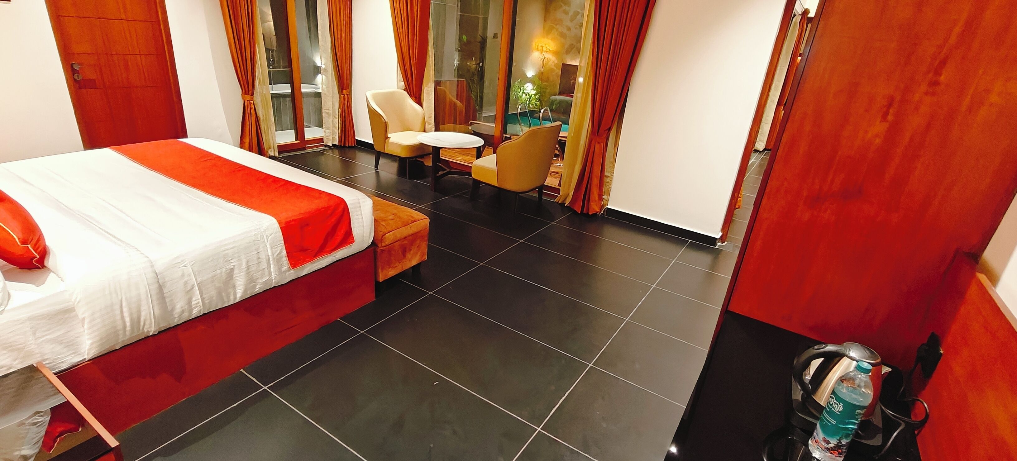 Una habitación de hotel con una cama, una mesita, dos sillas y una maleta.