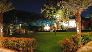 A well-lit garden with a gazebo, palm trees, and a pathway. - HF Pool Resorto (Chennai)